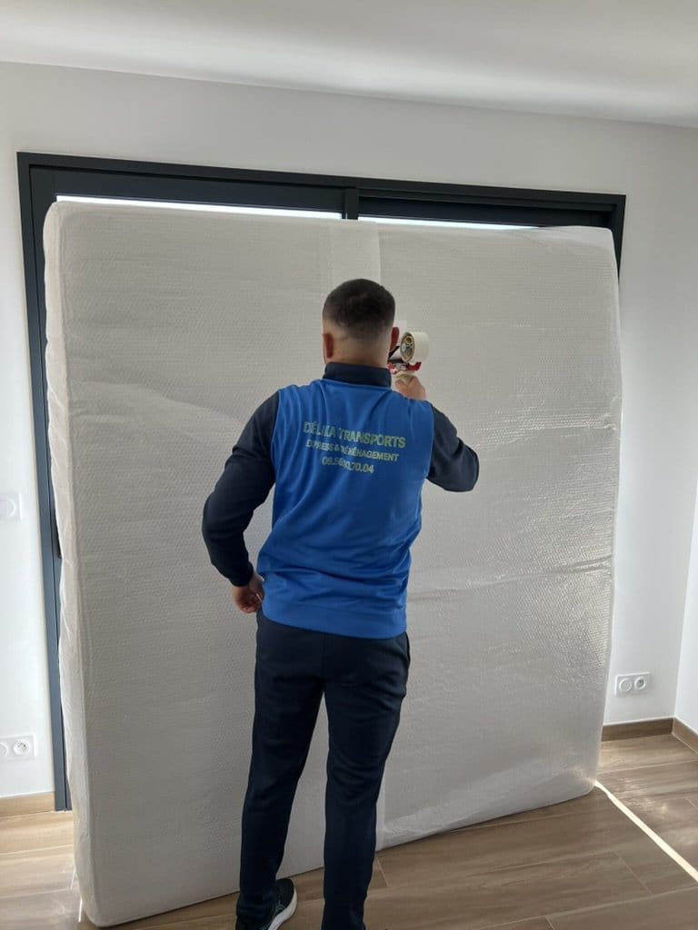 Un membre de l’équipe Délika Transports protège le mobilier avant le déménagement